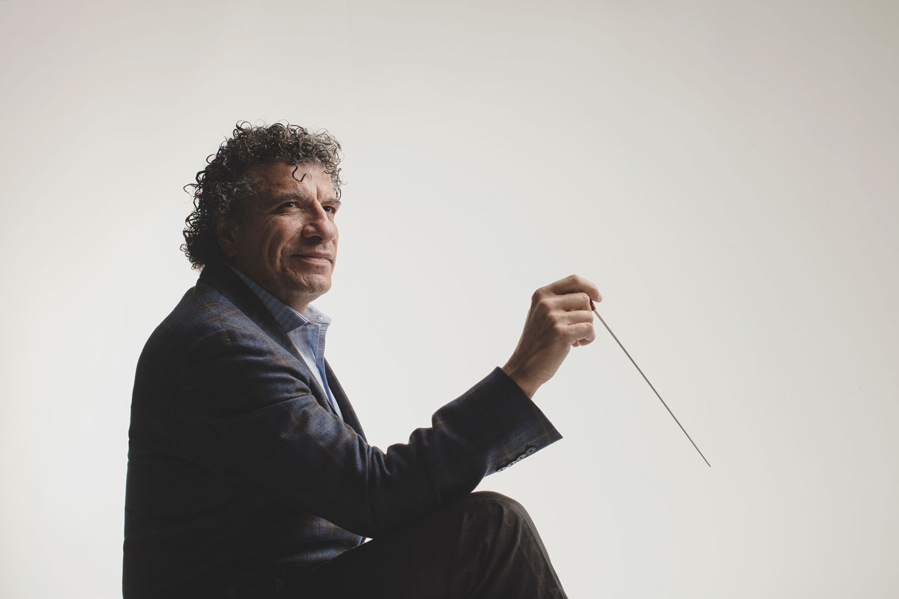 Giancarlo Guerrero former music director Nashville Symphony press photo conductor holding baton stands against white background